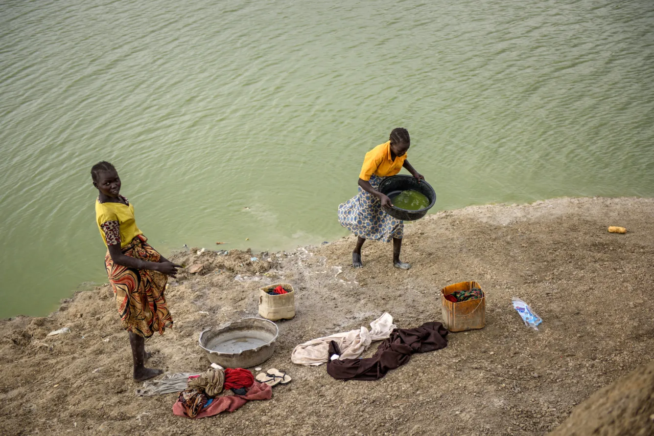 Girls collect water from an artificial lake to wash clothes
