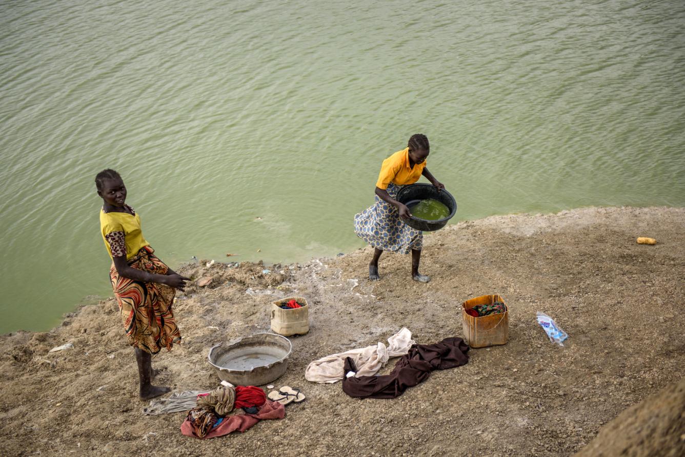Girls collect water from an artificial lake to wash clothes