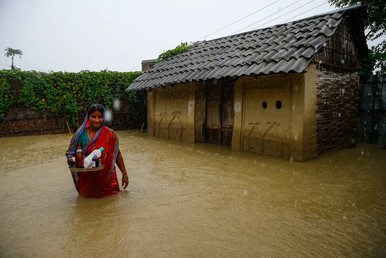 Une femme se trouve devant sa maison inondée dans le district de Saptari.