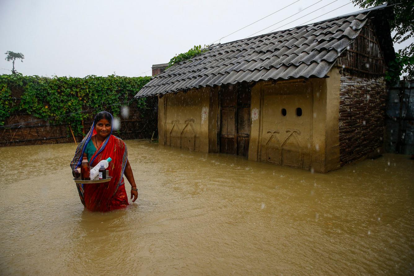 Une femme se trouve devant sa maison inondée dans le district de Saptari.