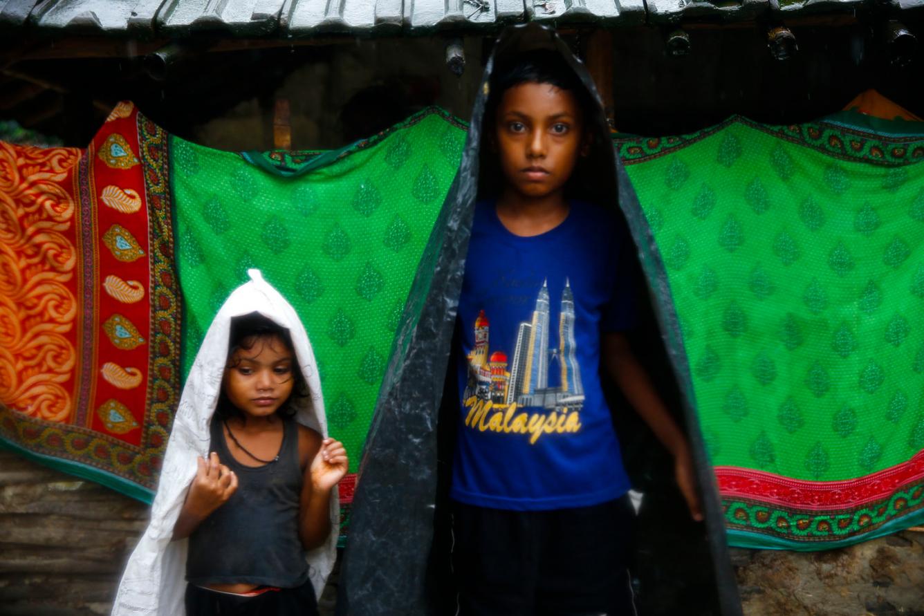 Deux jeunes utilisent des sacs en plastique en guise de bâches imperméables dans le district de Saptari.