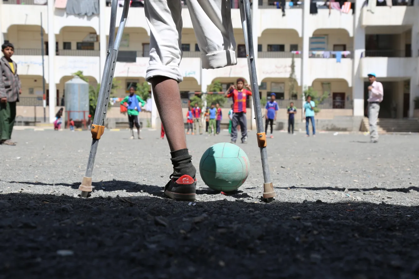 Rafik plays football with friends at school.