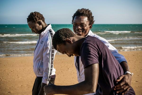 three youths laugh on a beach in Sicily