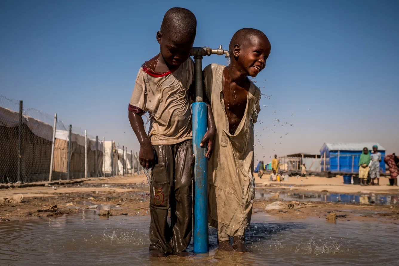 Enfants jouant sous un robinet d'eau au Nigéria