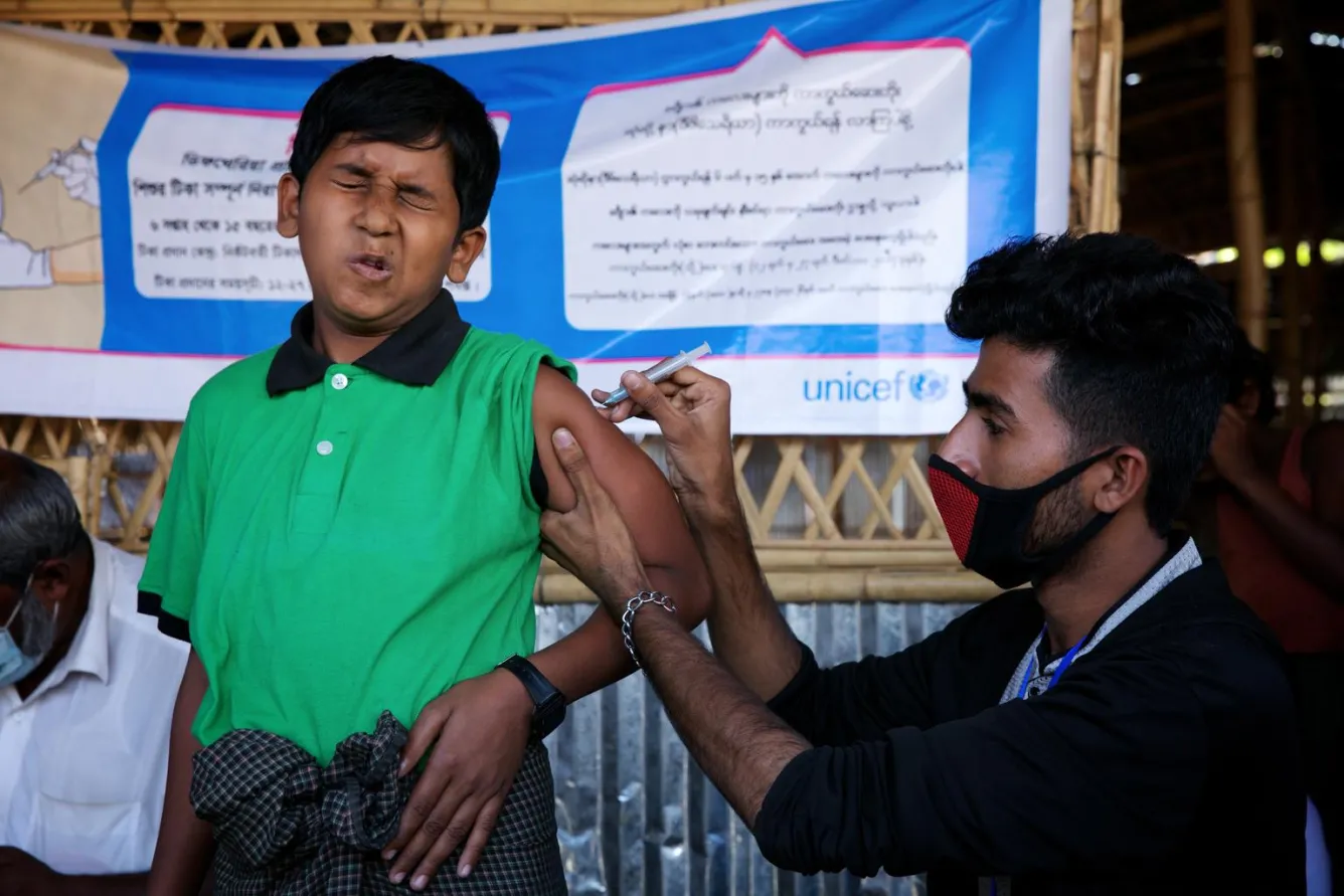 At a makeshift settlement for Rohingya refugees in Cox’s Bazar district, a child grimaces as he is administered a vaccine for diphtheria.