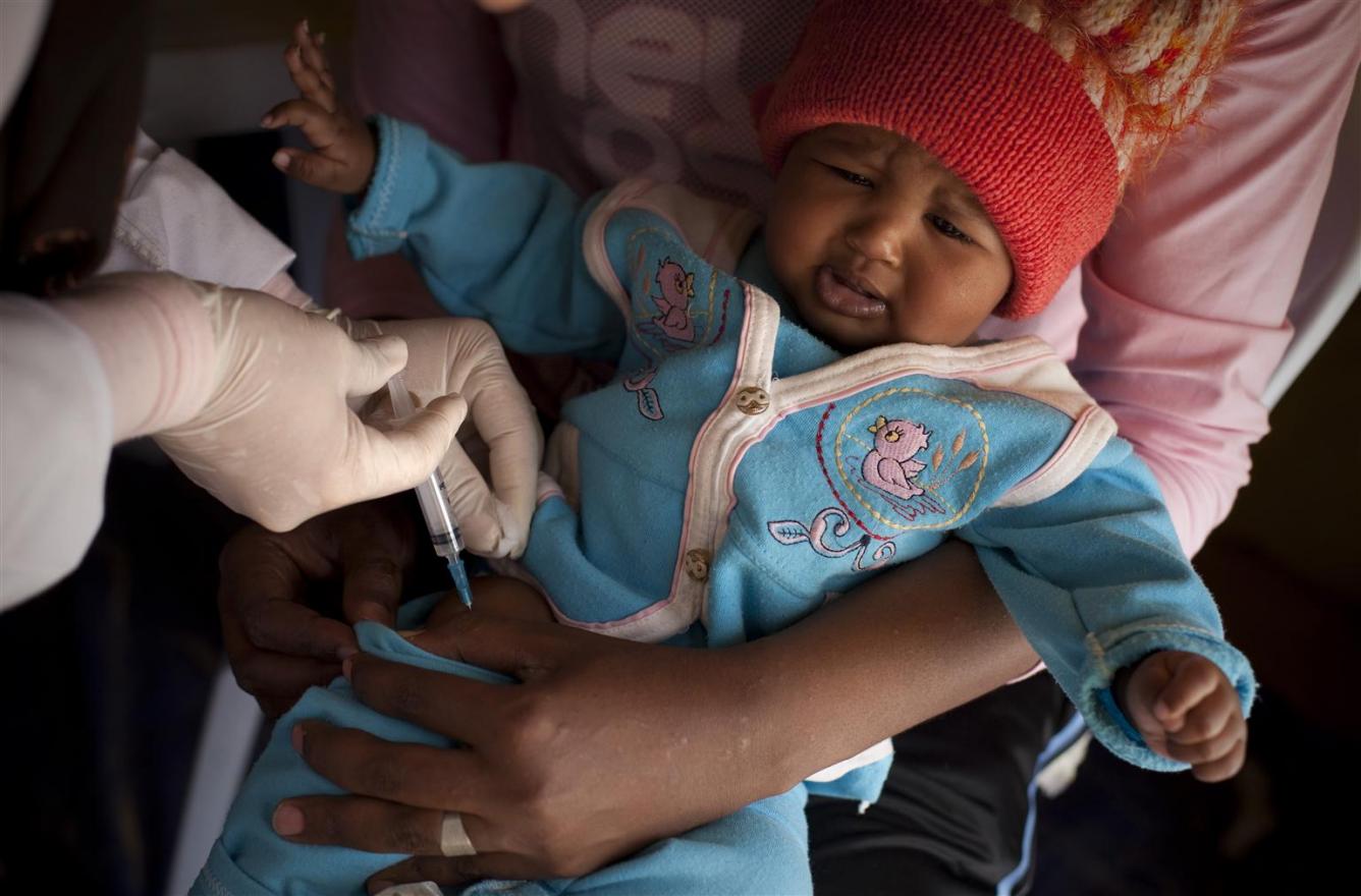An infant is vaccinated in a transit camp for third-country nationals fleeing the civil war in Libya, at the Ras Jedir border post.