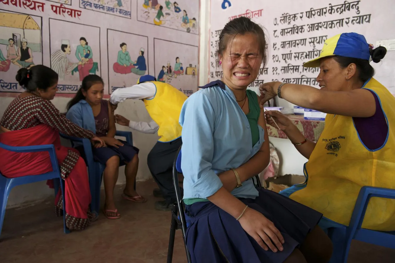 A schoolgirl is administered a measles-rubella vaccine at an immunization site in Ghermu Village.
