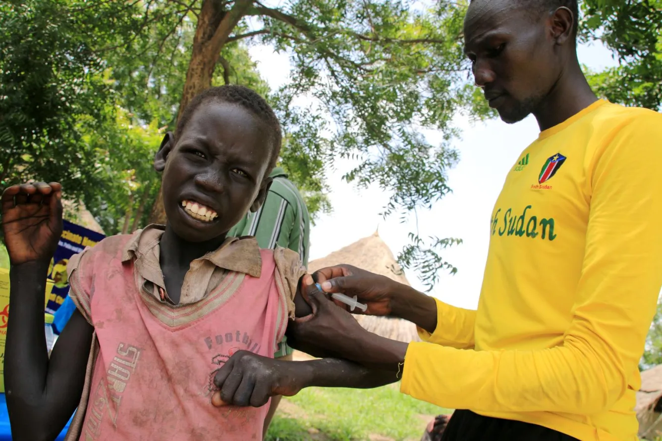 In the town of Kiech Kon, Upper Nile State, a health worker administers a vaccination to a boy.