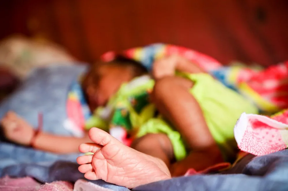 A newborn baby sleeps under a mosquito net