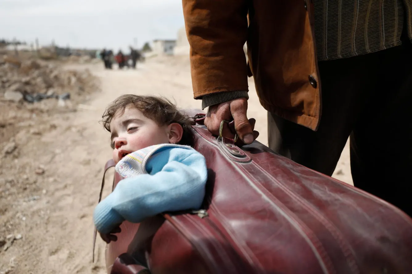 A Yemeni child is carried in a suitcase by an adult.