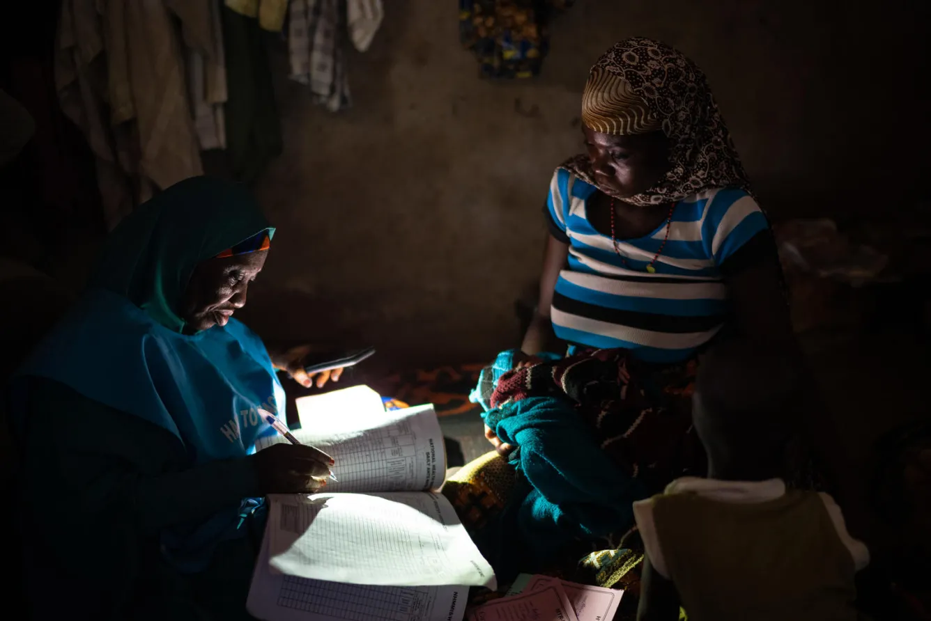 Une sage-femme de l’UNICEF prend des notes pendant une visite à domicile.
