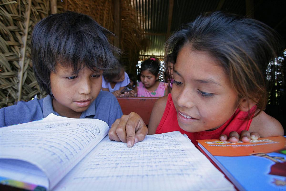 Children read a notebook together in a local school in a settlement for workers in Bolivia.