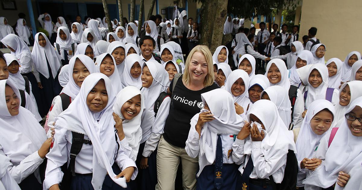A 25th team member in a black UNICEF T-shirt interacts with students on a field trip to Indonesia.