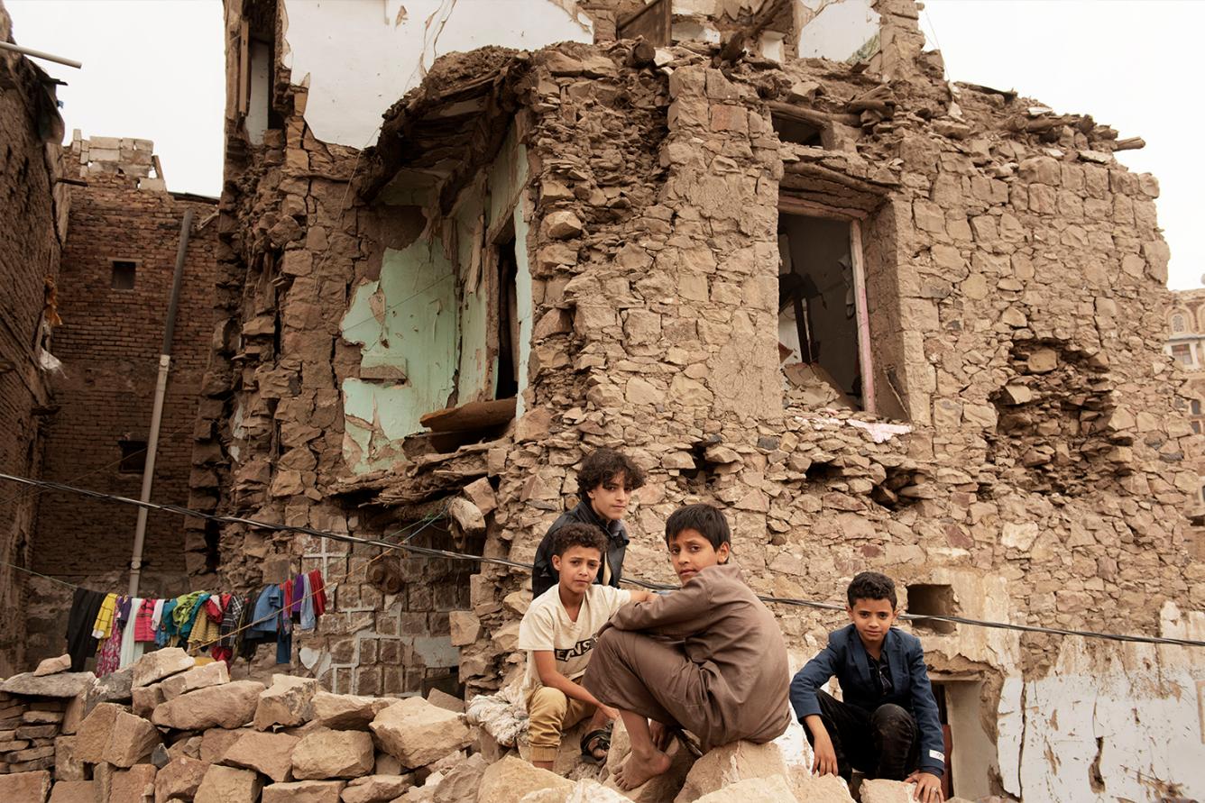 Des enfants sont assis devant une maison endommagée par une frappe aérienne dans la vieille ville de Sanaa, au Yémen (20 juillet 2019).