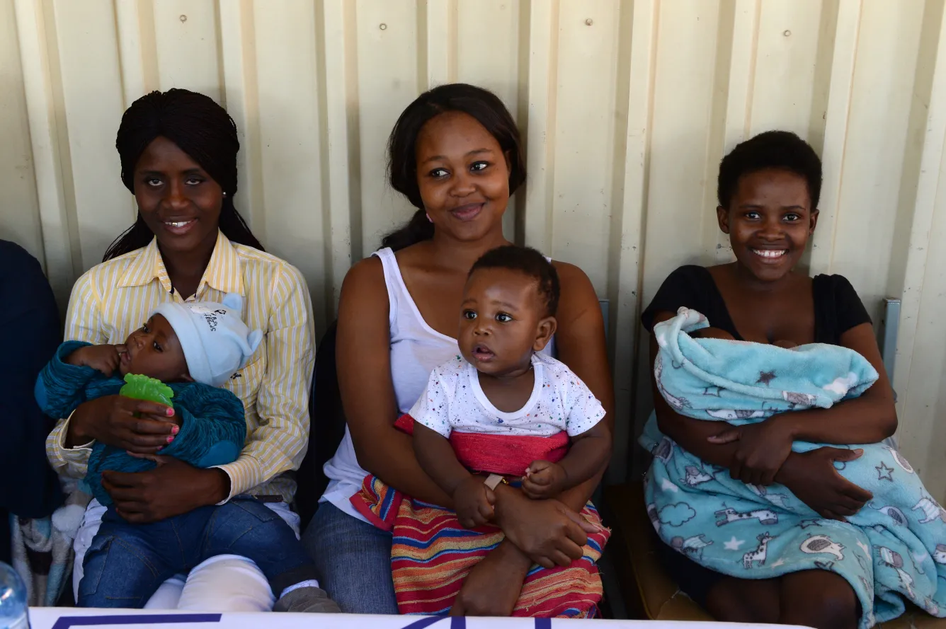 Three young mothers sitting with their children.