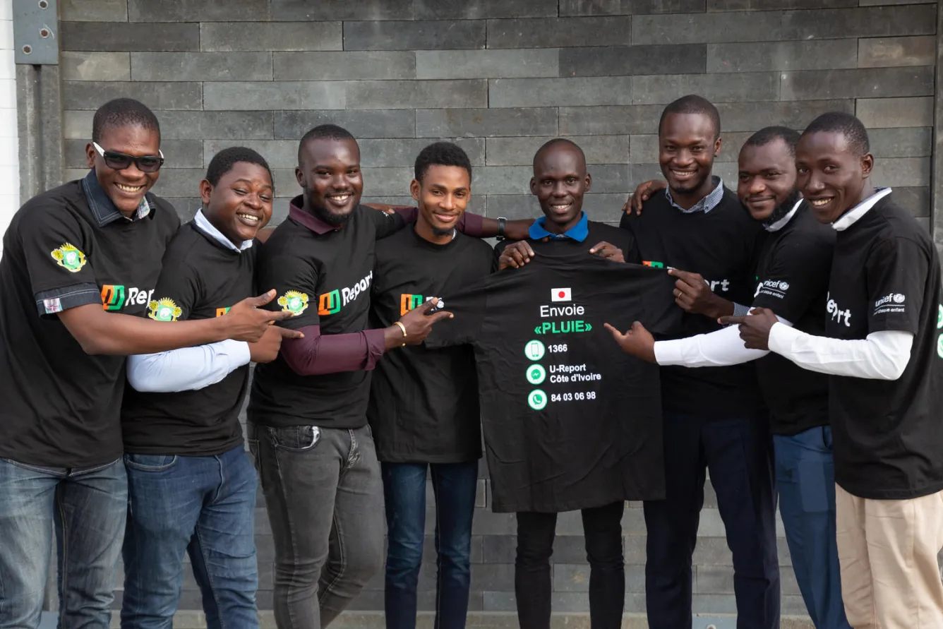 Smiling people pointing at the U-Report T-shirt.