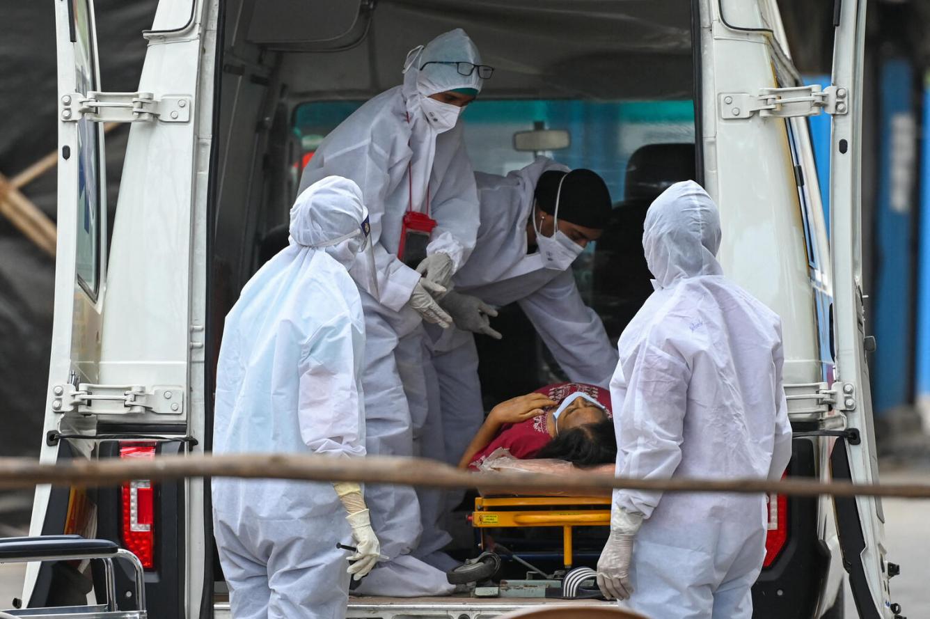 Health workers wearing Personal Protective Equipment (PPE) gear help a patient inside an ambulance at a recovery centre to treat Covid-19 in India.