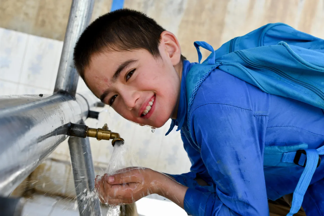 Un garçon boit de l’eau potable sur le terrain de jeu de l’école secondaire Sayef à Faizabad, en Afghanistan.