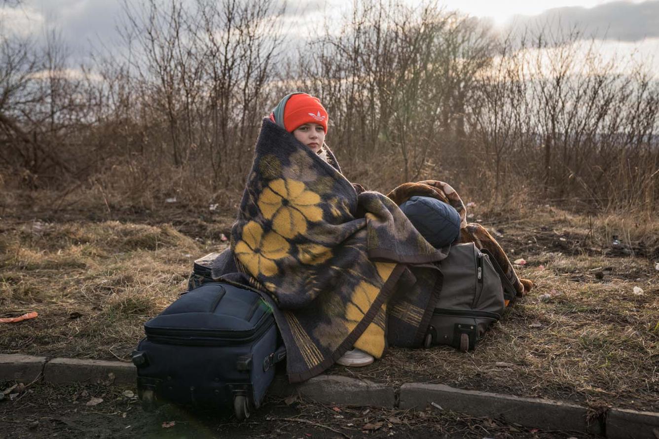 Girl sits by the road fleeing Ukraine