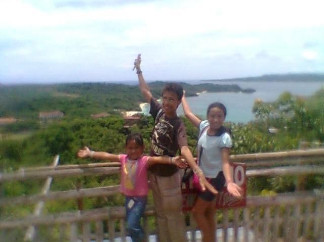 A young boy and 2 young girls stand with their arms spread out