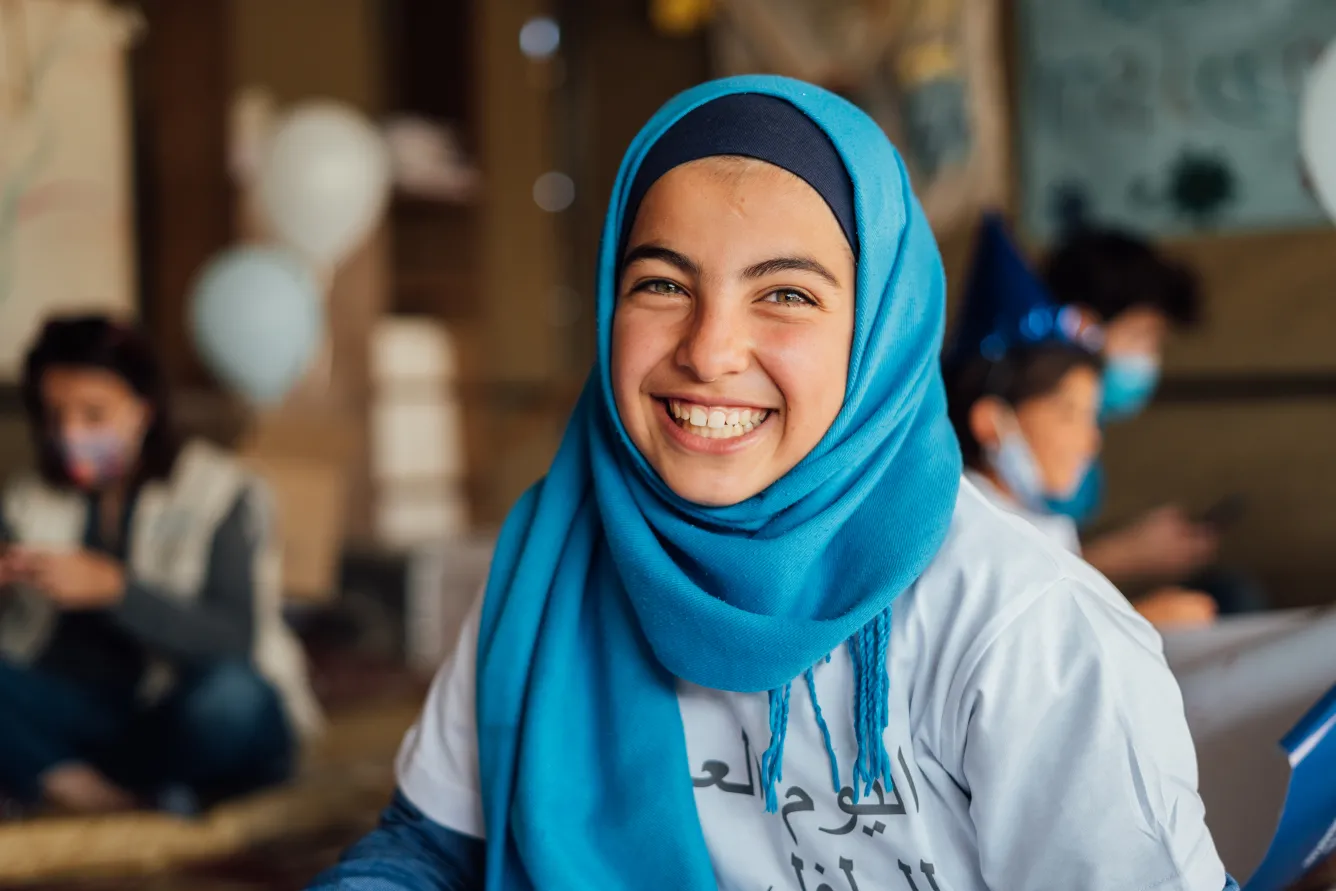 Une jeune fille est vêtue de bleu afin de célébrer les droits de l’enfant dans une installation informelle de tentes dans la périphérie d’Amman en Jordanie.