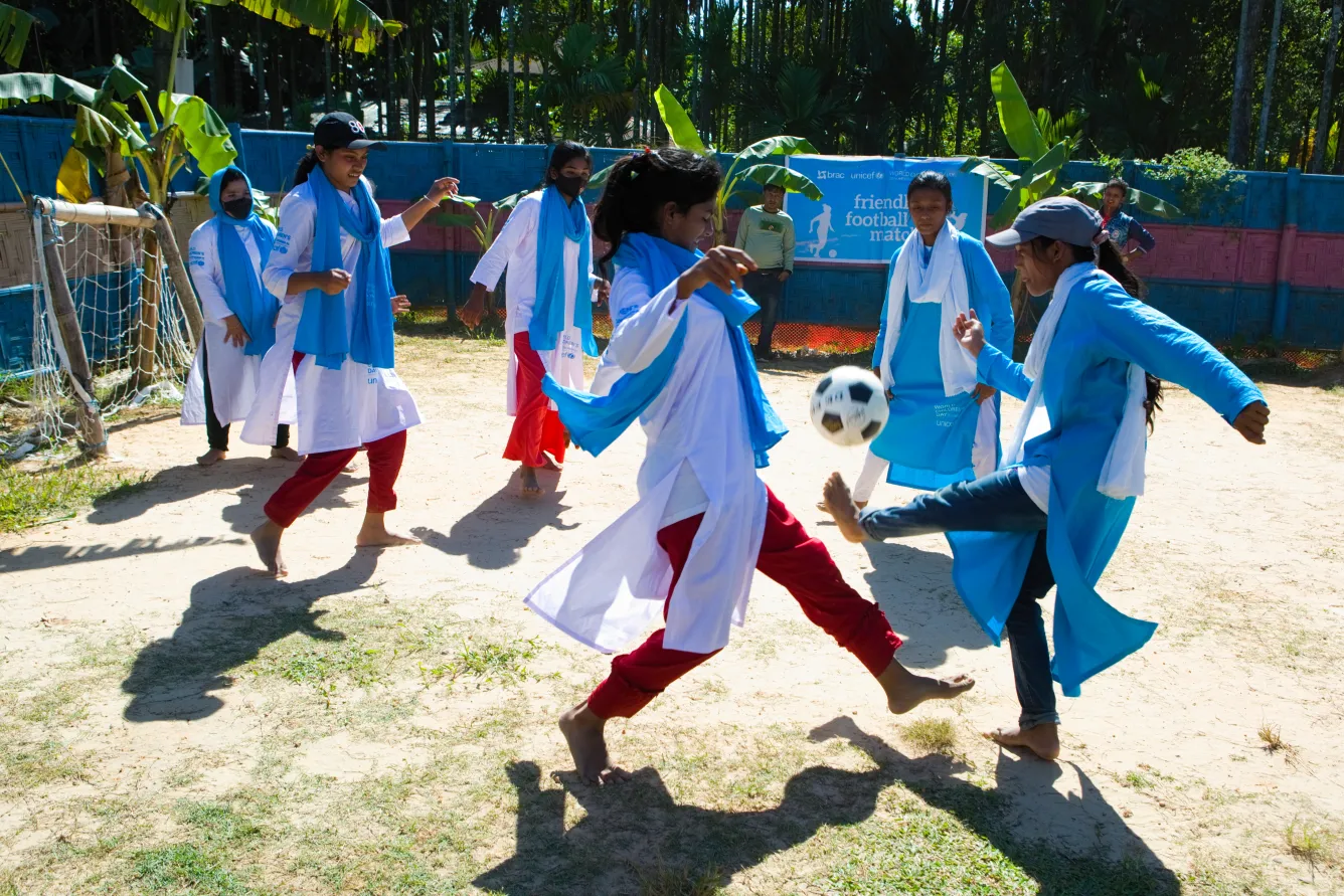Two girls spar over a soccer ball as their team members look on behind them in a soccer match in Cox's Bazaar, Bangladesh.