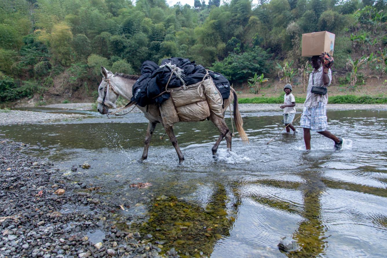 Les mulets et les hommes doivent traverser des cours d'eau pour permettre aux enfants des écoles éloignées de recevoir les kits scolaires.