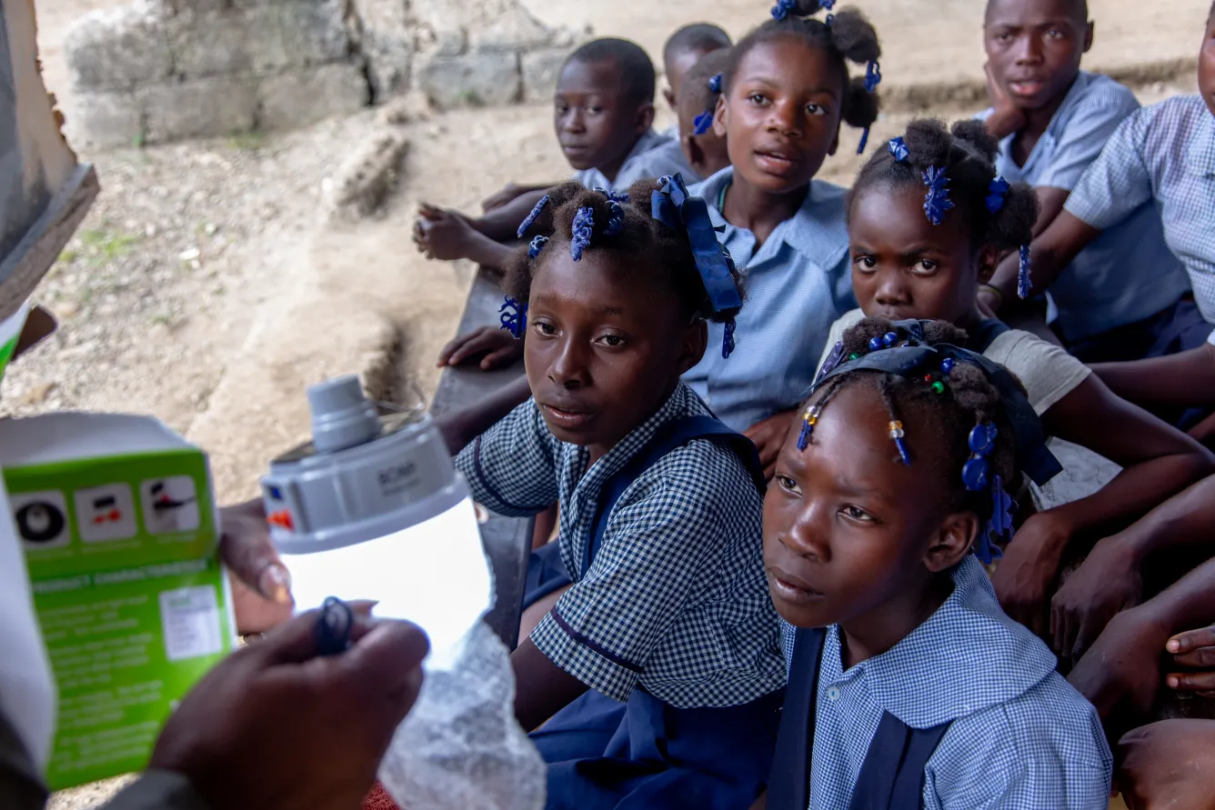 A teacher shows how to use the solar lamp to the students of Galette Cotonnier in Grande Anse.