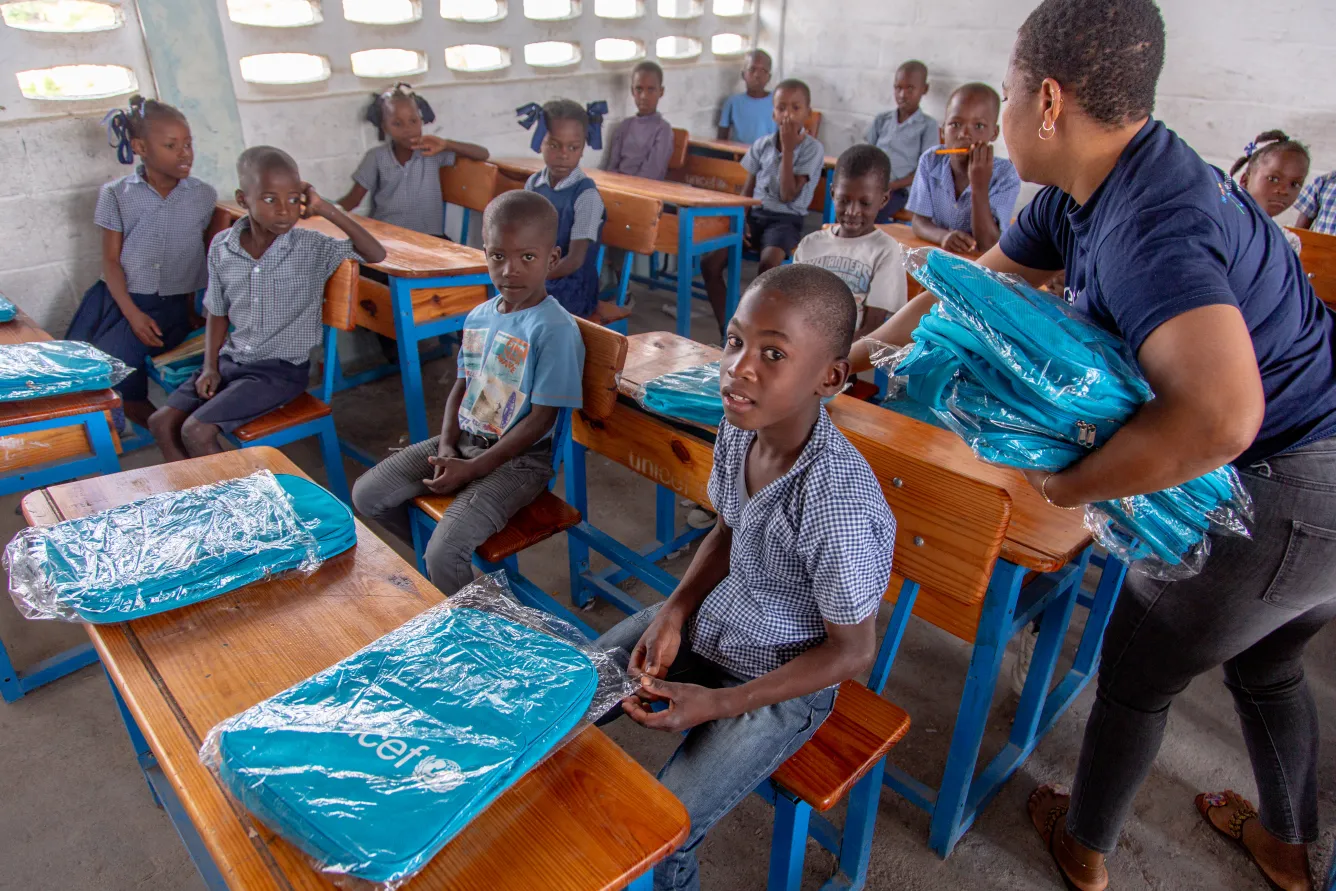 Darlee Labranche, UNICEF Education Officer distributes school materials to students at Morency National School, South, Haiti.