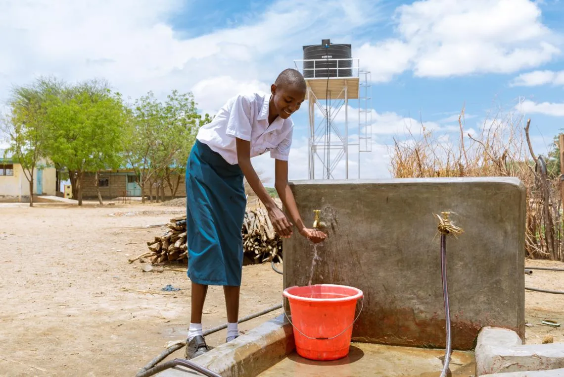 Sharlyne remplit un seau d’eau potable à l’école primaire de Nabulon.