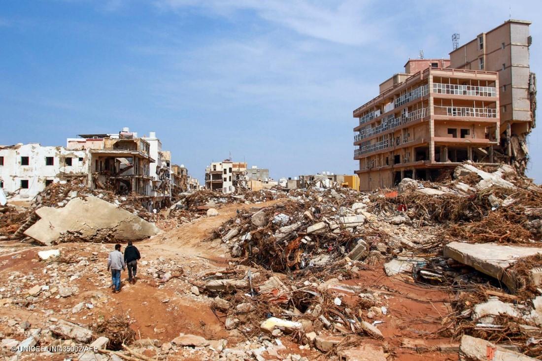 Two men walk past debris of destroyed buildings after flash floods in Derna, eastern Libya, on Sept. 11, 2023.