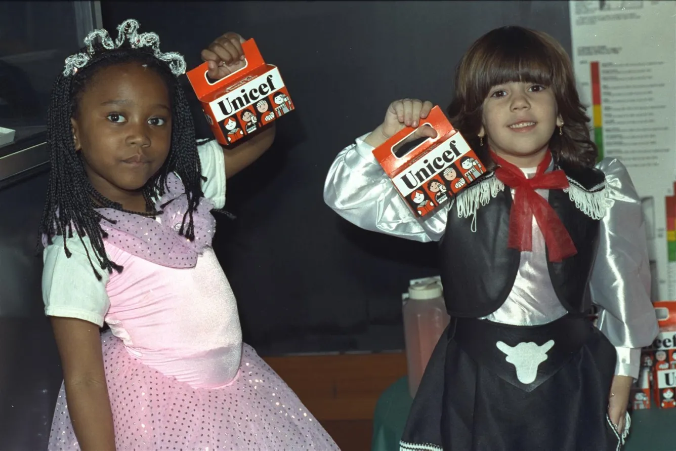 Deux filles déguisées portent des tirelires orange.