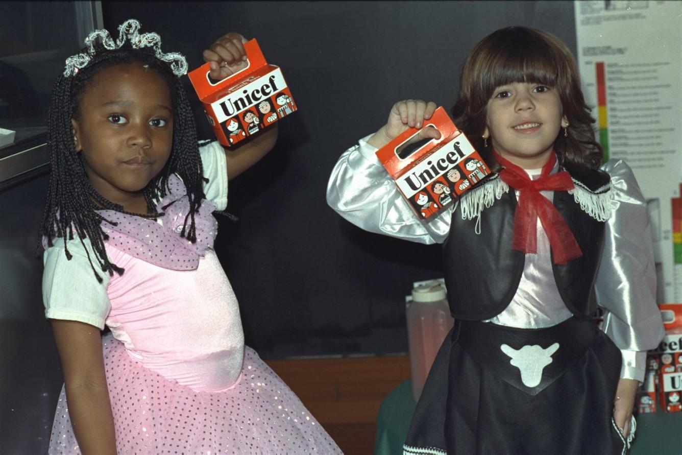 Deux filles déguisées portent des tirelires orange.