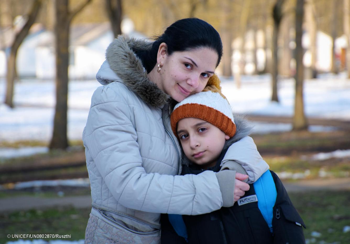 Une mère serre dans ses bras son fils portant des vêtements d’hiver en Ukraine.