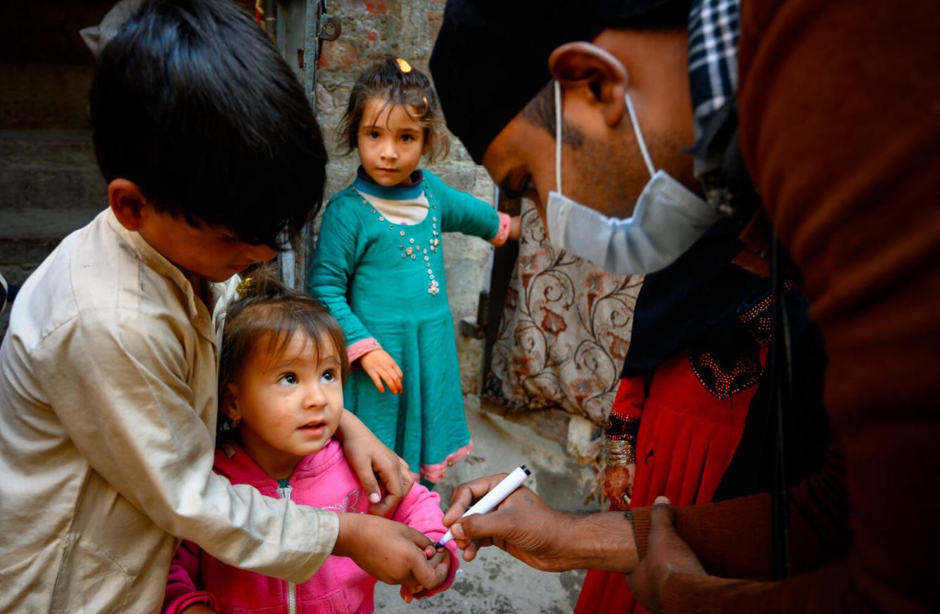 A polio vaccinator in Lahore, Pakistan, marks the finger of a two-year-old girl after giving her the polio vaccine.