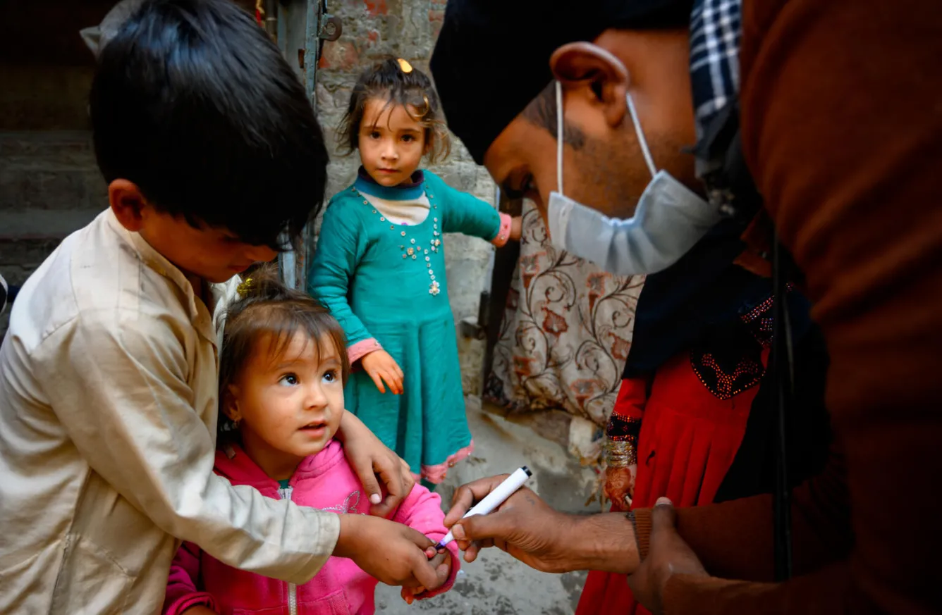 À Lahore, au Pakistan, un vaccinateur marque le doigt d’une petite fille âgée de deux ans après lui avoir administré le vaccin contre la poliomyélite.