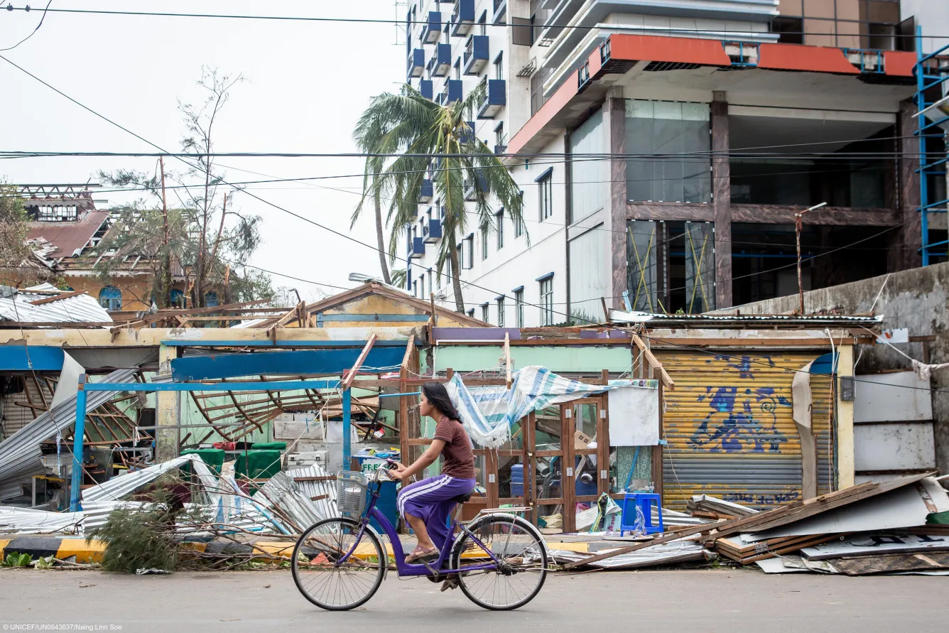 A woman cycles past buildings that were badly damaged during Cyclone Mocha in Rakhine State, Myanmar,