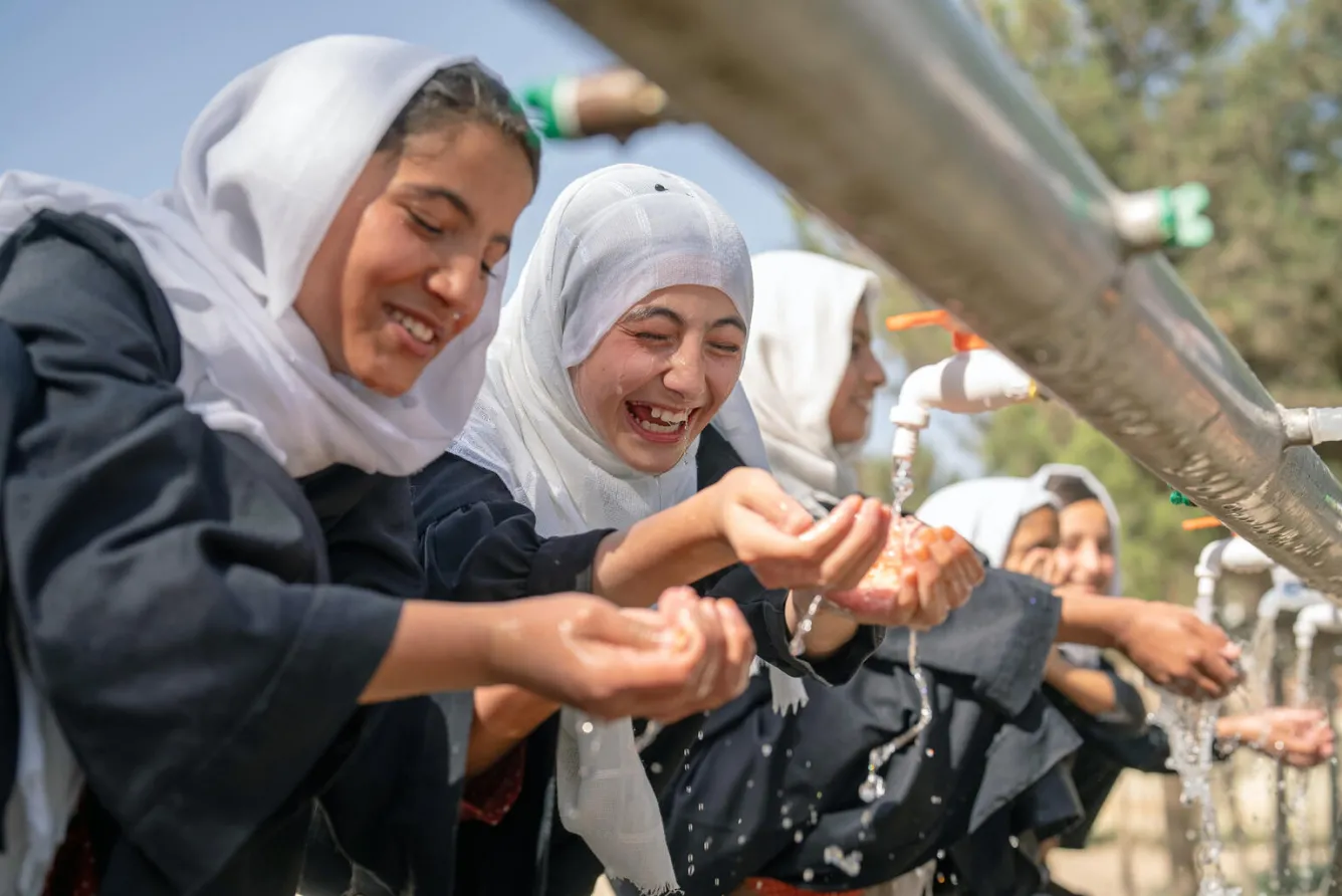 Des filles se lavent les mains à une installation extérieure de lavage des mains en Afghanistan.