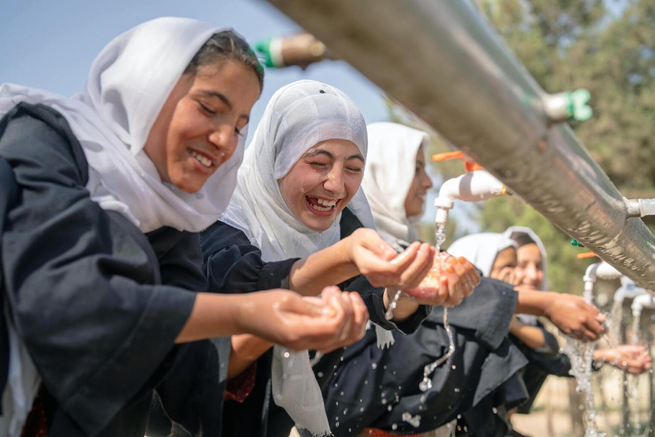 Des filles se lavent les mains à une installation extérieure de lavage des mains en Afghanistan.