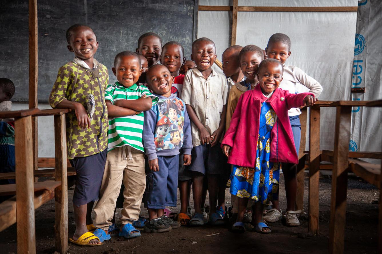 A group of children smile at the camera at a UNICEF-supported temporary learning space in The Democratic Republic of the Congo.