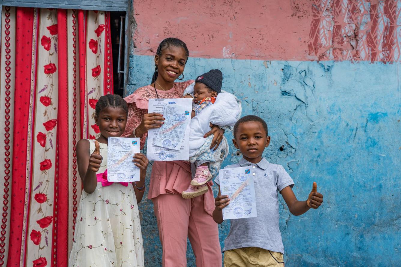 À Kinshasa, en République démocratique du Congo, Noëlla brandit l’acte de naissance de son nouveau-né, tandis que ses deux autres enfants brandissent le leur.