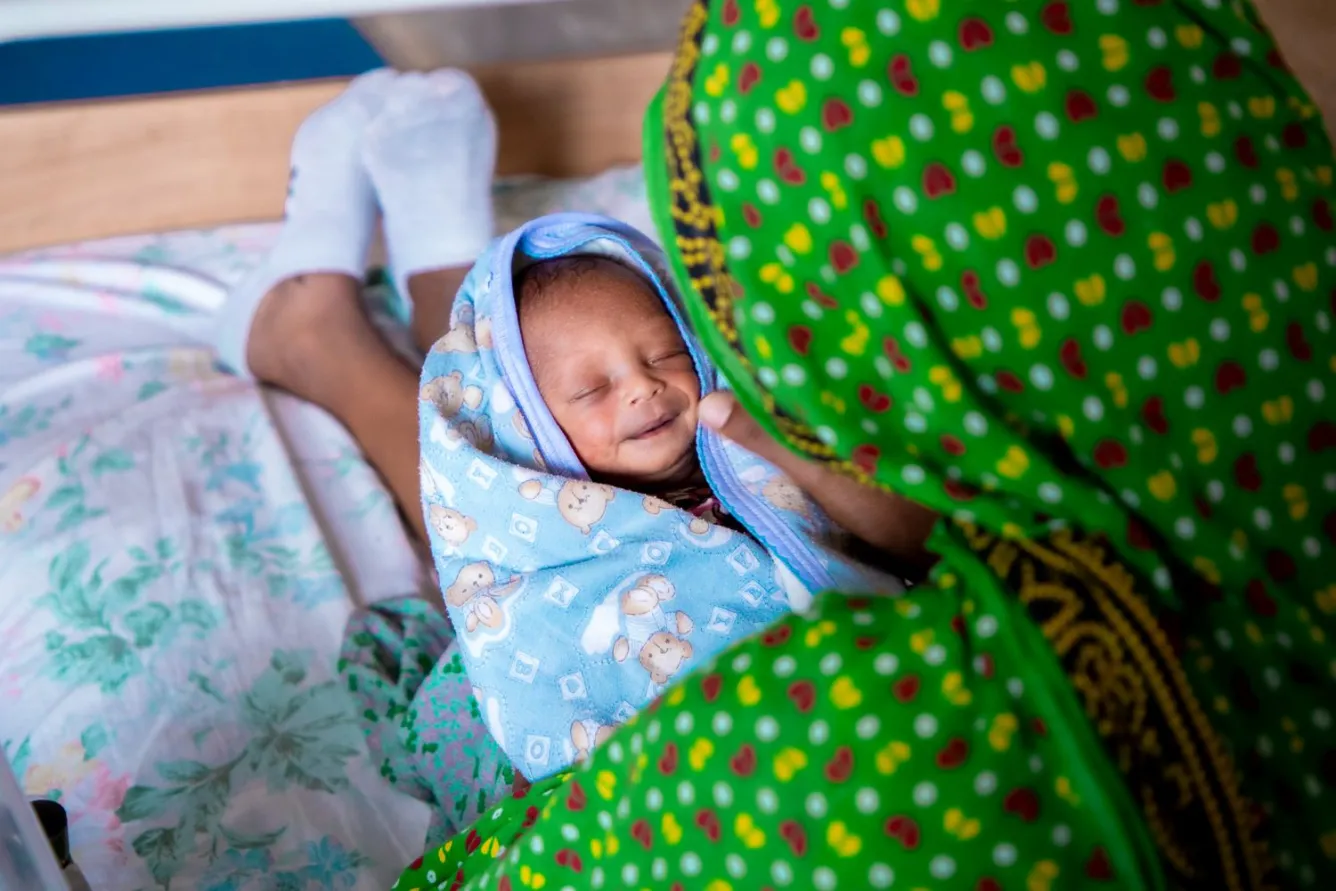 In a hospital in Ethiopia, a baby wrapped in a blanket is held by her mother.