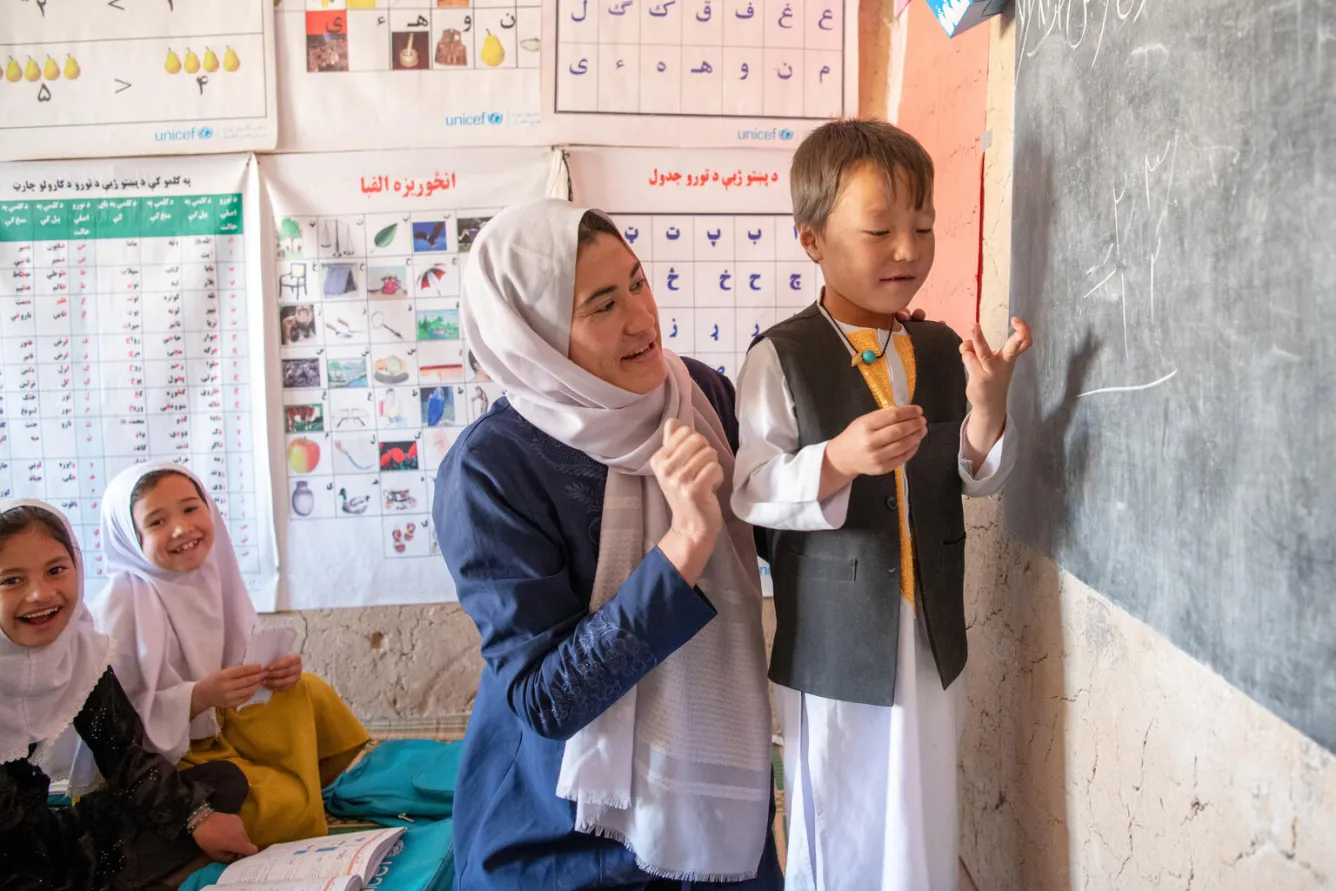 Teacher Ruqiya helps 7-year-old Milad with his math lesson at the UNICEF-supported community-based education class.