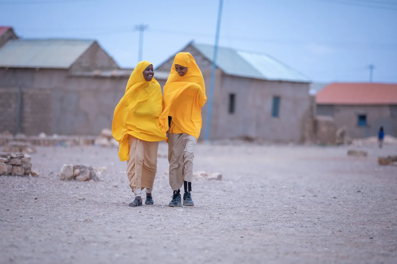 Two girls walk happily in their tangerine school uniforms