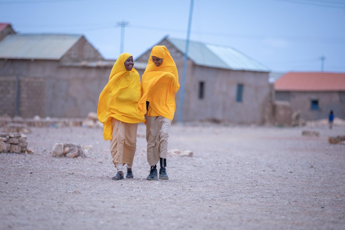 Two girls walk happily in their tangerine school uniforms