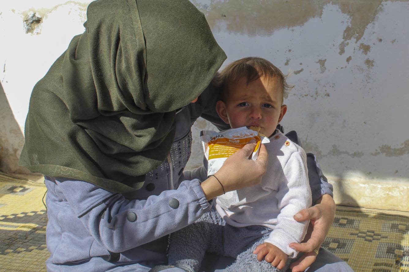 Abeer, Morei’s mother, gives her one-year-old son a preventive food supplement in the yard of their home in Obada village, Rural Damascus, Syria.