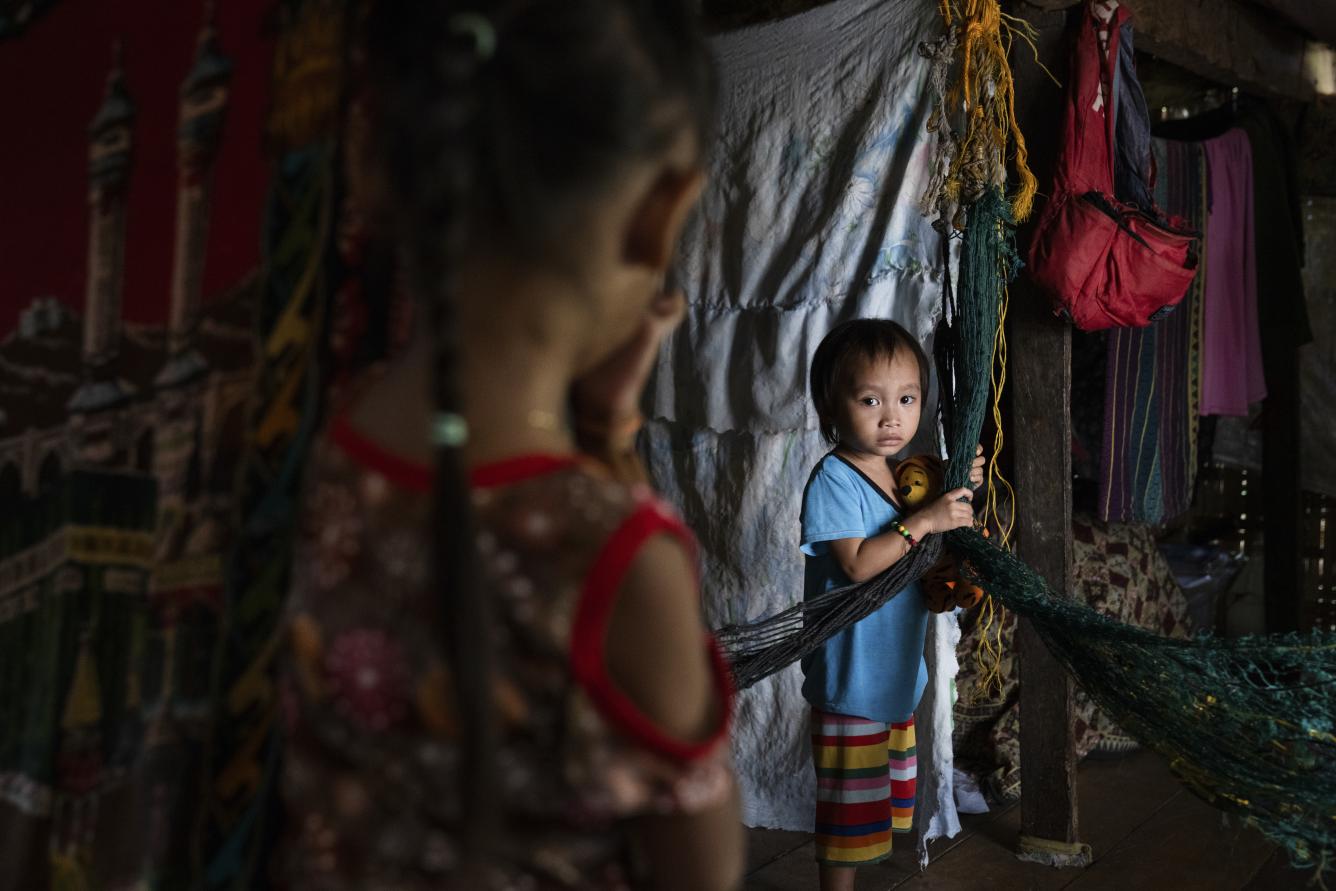 Two children stand inside their home in Cotabato City, Philippines where they live with their extended family. Their cousins were infected with the measles virus during an outbreak in the region.