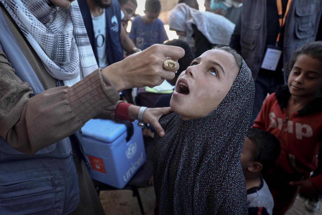 A girl receives the oral polio vaccine from a health worker.