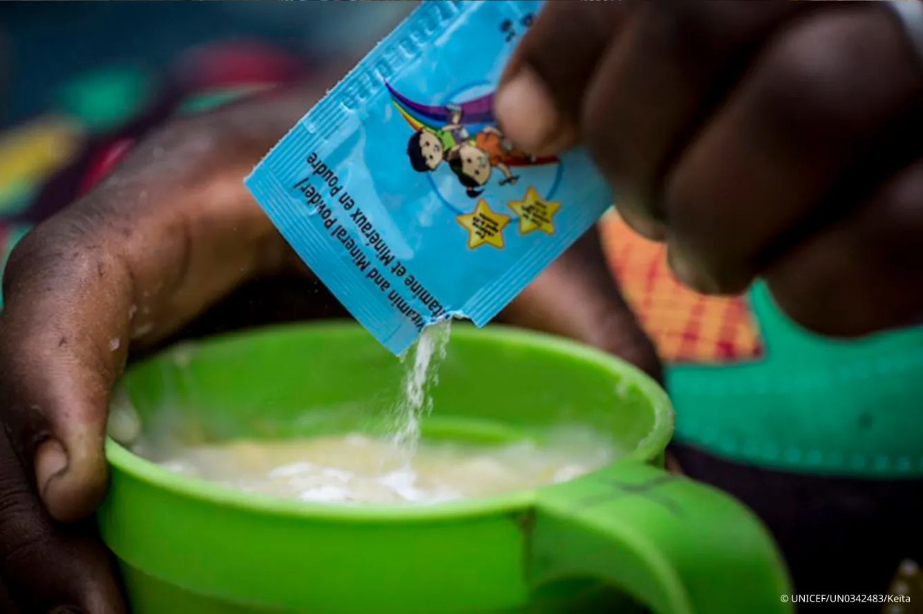 Une personne ajoute un sachet de micronutriments en poudre dans une tasse.