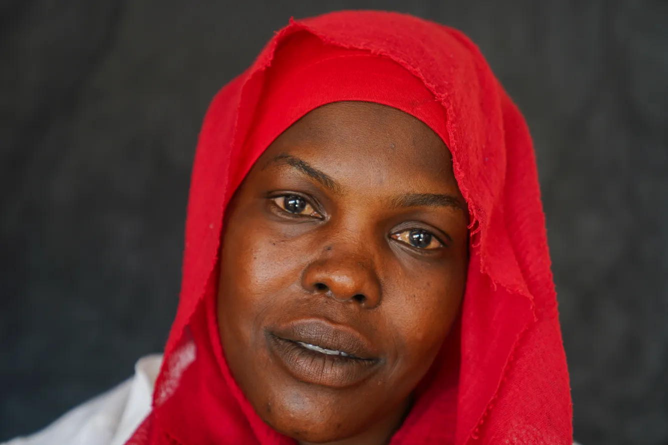 A woman wearing a red headscarf looks at the camera. 